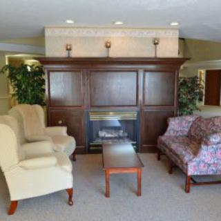 A cozy living room with a fireplace, featuring comfortable seating and decorative plants.