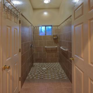 A well-lit bathroom featuring tiled walls and floor with multiple doors leading into the shower area.