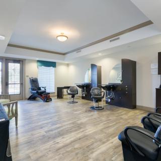 A modern salon interior featuring chairs, mirrors, and wooden flooring.