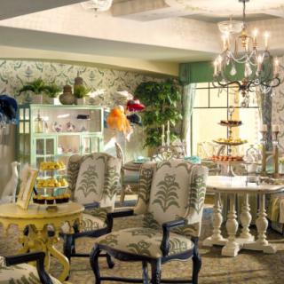 A cozy and elegant vintage-style interior featuring a floral-patterned decor, ornate furniture, and a chandelier.