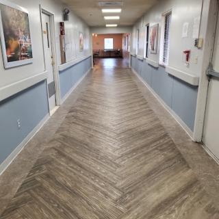 A well-lit corridor featuring a herringbone patterned floor and wall decorations.