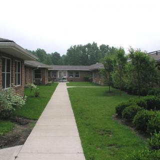 A serene pathway lined with greenery leading to a residential building.