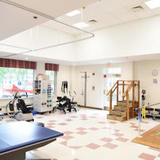 A spacious physical therapy room equipped with various exercise machines and a step platform for rehabilitation activities.