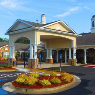 A beautifully designed building entrance with manicured landscaping and a circular driveway.