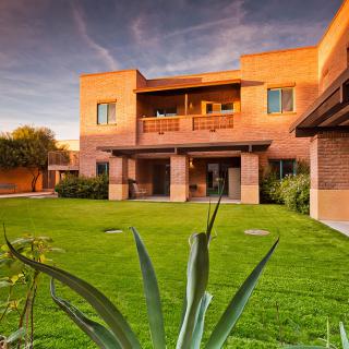 A modern house with a spacious green lawn at sunset.