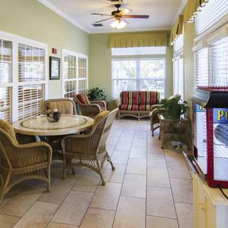 A bright sunroom with wicker furniture, large windows, and a popcorn machine.