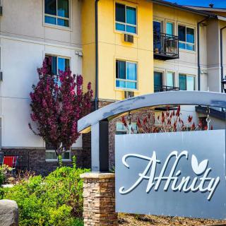 A modern apartment complex with a prominent sign reading 'Affinity' amidst well-maintained landscaping.