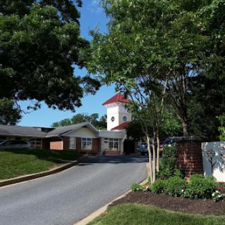 A picturesque view of a building surrounded by lush greenery and a clear blue sky.