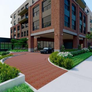 A modern residential building with a brick exterior and landscaped surroundings, featuring a curved driveway.
