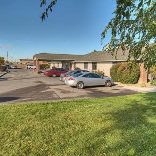A small building with a parking lot and several parked cars on a sunny day.