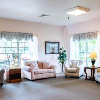A cozy living room with sofas, armchairs, and large windows allowing natural light in.