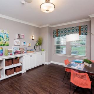 A colorful classroom setup with art supplies and storage, featuring bright chairs and a large window.