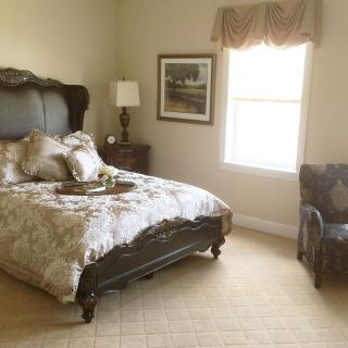 A cozy bedroom with a large bed, elegant furnishings, and soft lighting.