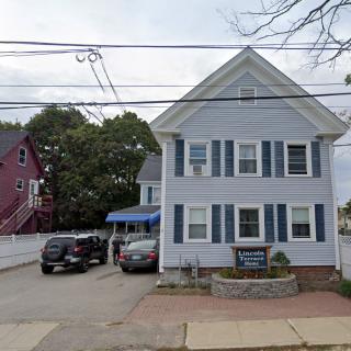 A residential house with blue shutters and cars parked in the driveway.