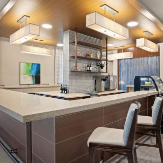 A modern bar interior featuring a sleek design with seating, contemporary lighting, and a minimalist countertop.