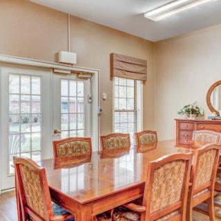 A well-lit dining room featuring a large wooden table and chairs with windows allowing natural light in.