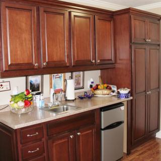 A kitchen interior with wooden cabinets, a small fridge, and various items on the countertop.