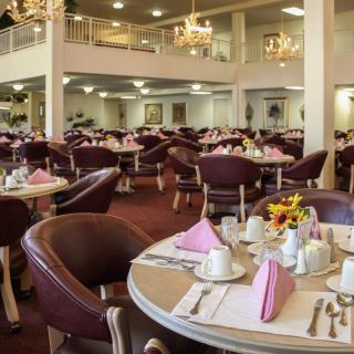 An elegant dining room with neatly arranged tables and chairs, adorned with chandeliers.