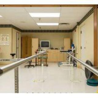 A rehabilitation room equipped with parallel bars and exercise equipment.