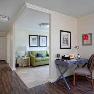 A cozy living space with a green sofa, desk area, and artwork on the walls.
