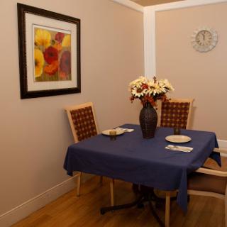 A cozy dining area featuring a blue tablecloth, floral centerpiece, and decorative wall art.
