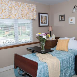 A cozy bedroom featuring a comfortable bed, fresh flowers, and a serene view through the window.