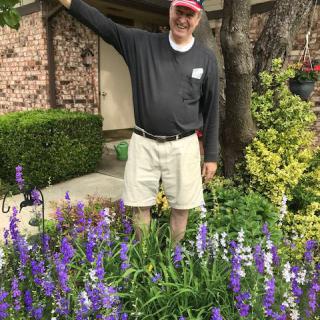 A person standing in a garden with blooming flowers.