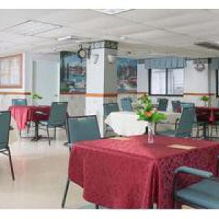 An empty dining area with tables covered in red tablecloths and neatly arranged chairs.
