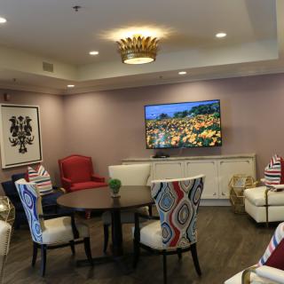 A stylish living room with colorful chairs, a TV mounted on the wall, and elegant lighting.
