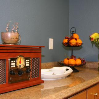 A cozy kitchen corner with a vintage radio and a tiered fruit bowl on the countertop.