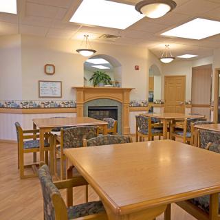 A cozy dining area with multiple wooden tables and chairs, illuminated by ceiling lights.