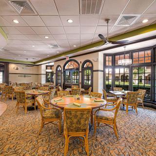 A spacious restaurant interior with wicker chairs and tables set in a well-lit dining area.