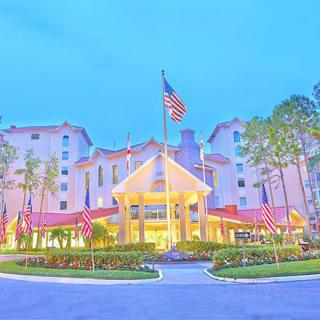 A brightly lit hotel entrance with multiple flags and surrounding trees.