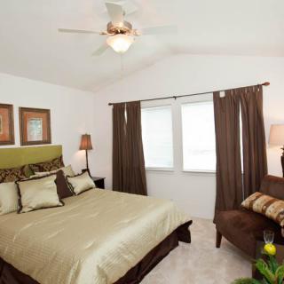 A cozy bedroom featuring a large bed with green accents, brown curtains, and tasteful decor.