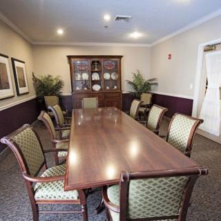 A formal conference room with a long wooden table and upholstered chairs.