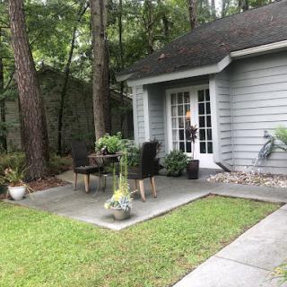 A serene outdoor patio area surrounded by trees, featuring comfortable seating and decorative plants.
