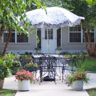 A cozy outdoor seating area with a decorative umbrella and vibrant flowers, perfect for enjoying the fresh air.