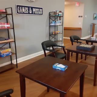A cozy recreational area featuring tables and chairs for games, with shelves stocked with various game materials.