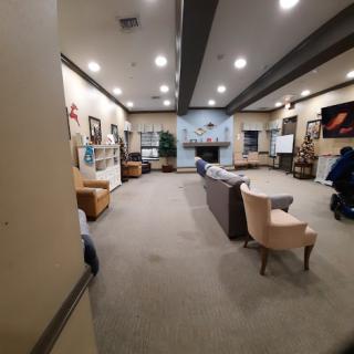 A spacious community lounge area featuring comfortable seating and wall art.