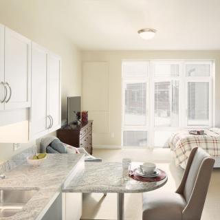 A modern, minimalist kitchen and living room with an open floor plan and ample natural light.