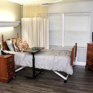 A well-furnished hospital room featuring a patient bed, wooden furniture, and a television.