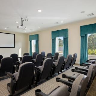 A well-organized conference room with theater-style seating and a projector screen.
