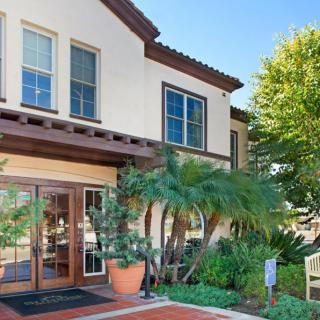 A modern residential building with a landscaped entrance and large windows.