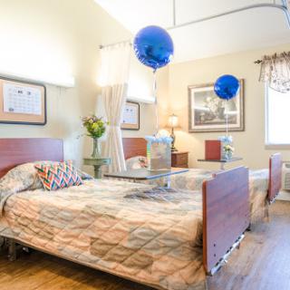 A well-lit hospital room featuring two beds, decorative elements, and blue balloons.