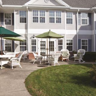 A residential patio area with chairs and umbrellas on a sunny day.