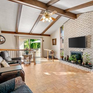 Spacious living room with a vaulted ceiling, exposed beams, and a brick fireplace.