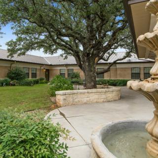 A serene courtyard with a central fountain, surrounded by greenery and buildings.