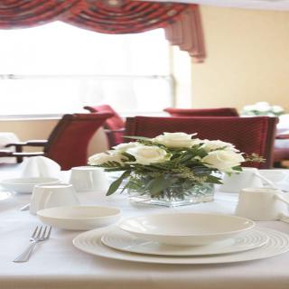 An elegant dining table set with white plates and a floral centerpiece.