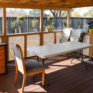 A cozy outdoor patio with a table and chairs on a wooden deck.