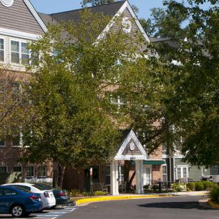 A residential building with parked cars and surrounding trees.